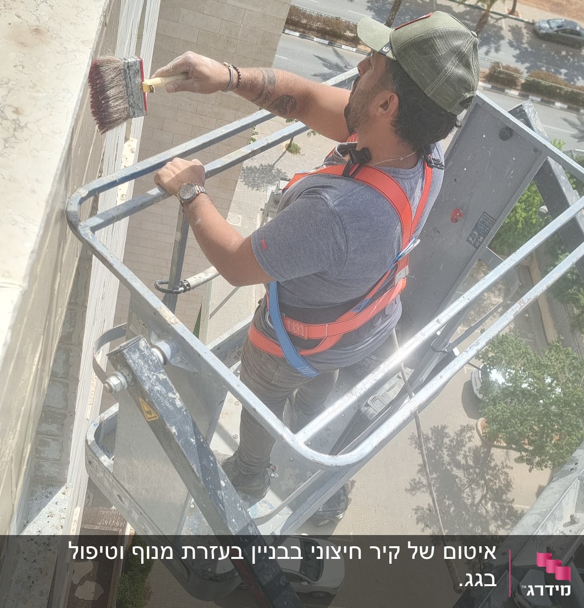 אדם במנוף צובע קיר חיצוני במברשת